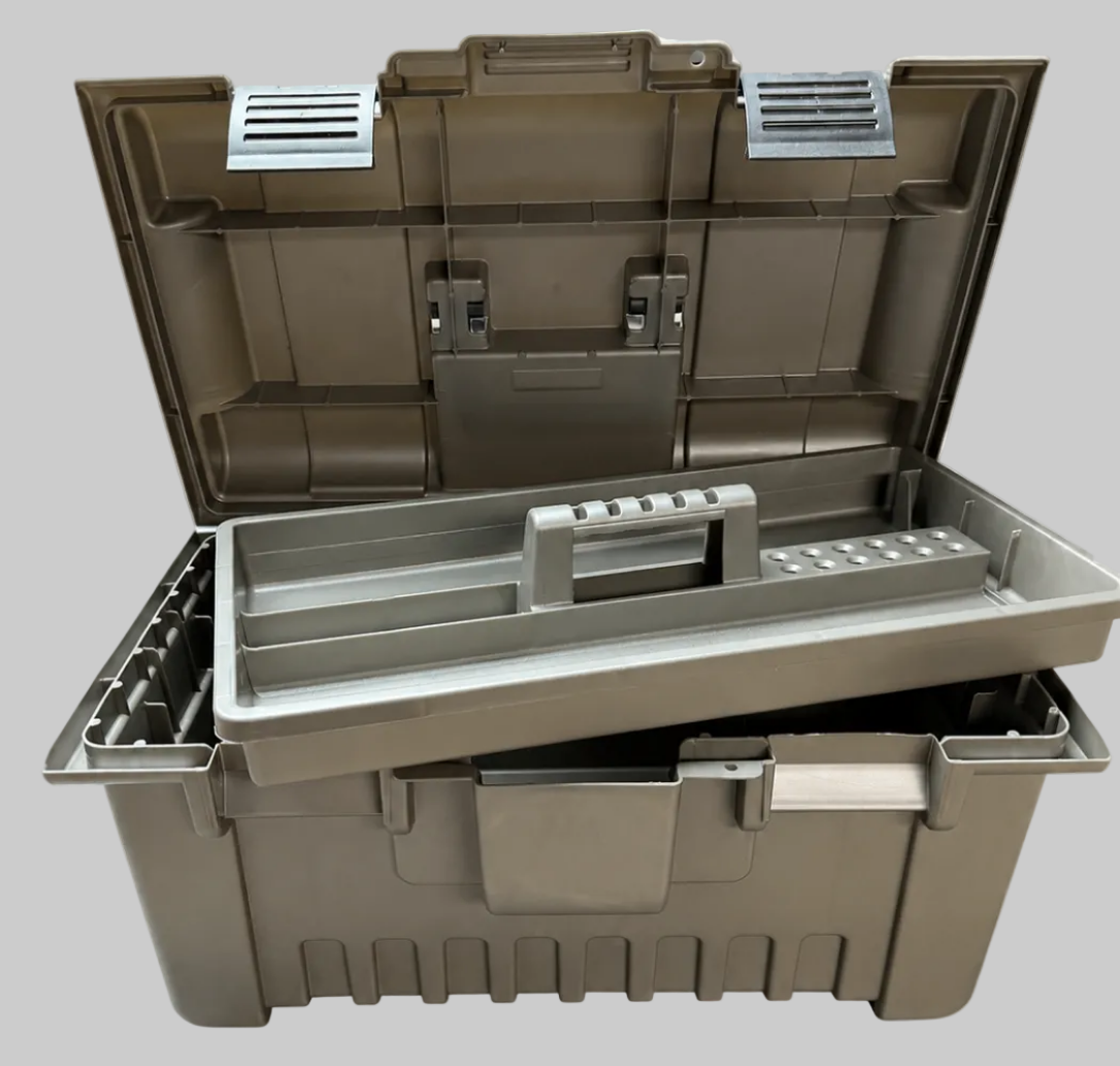 A rugged plastic storage toolbox shown open, with a gray organizer tray resting across the top. The toolbox is a muted taupe-brown color, and the background is a white and gray checkerboard pattern indicating a transparent cutout.