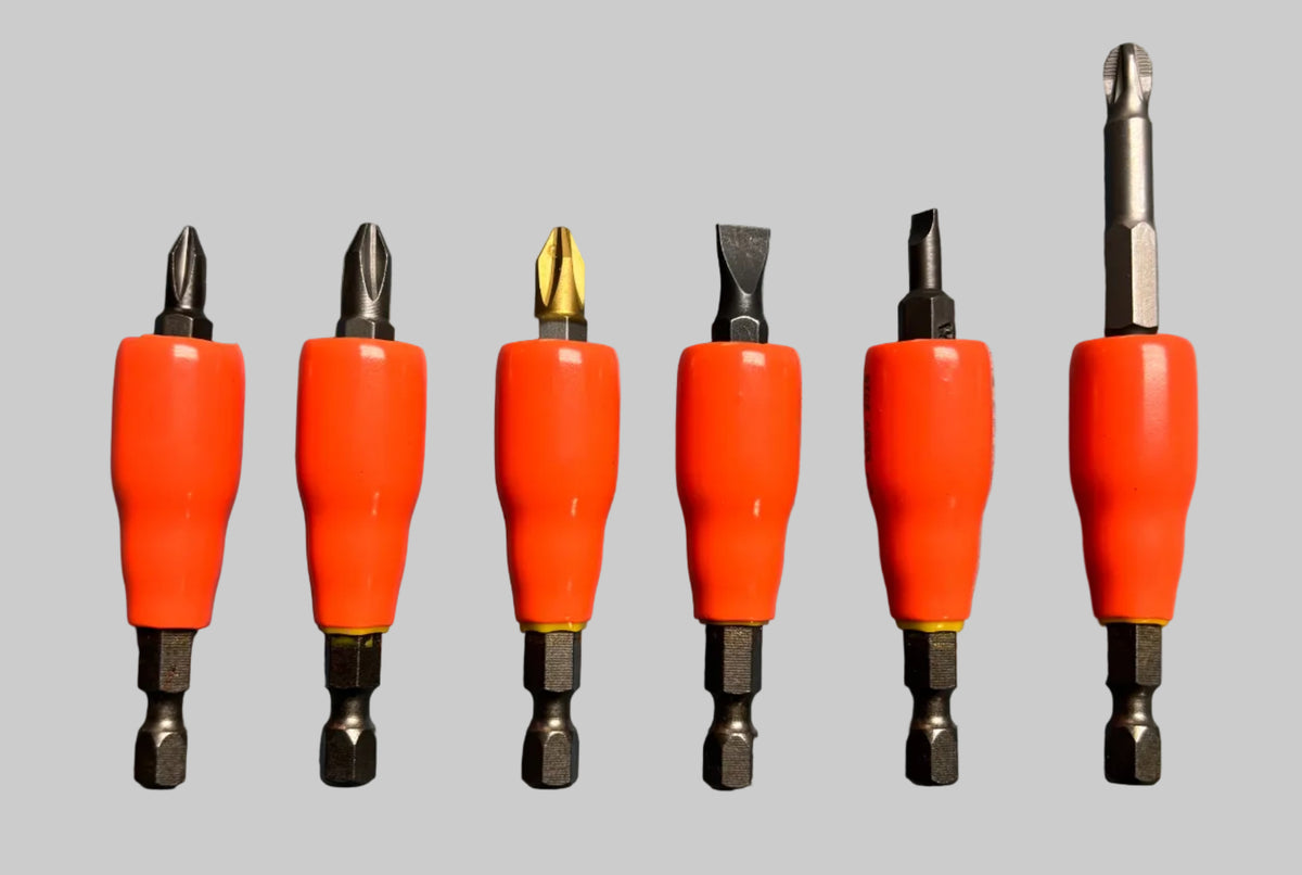 Six screwdriver bit sets with bright orange handles arranged in a row on a textured blue-gray surface.