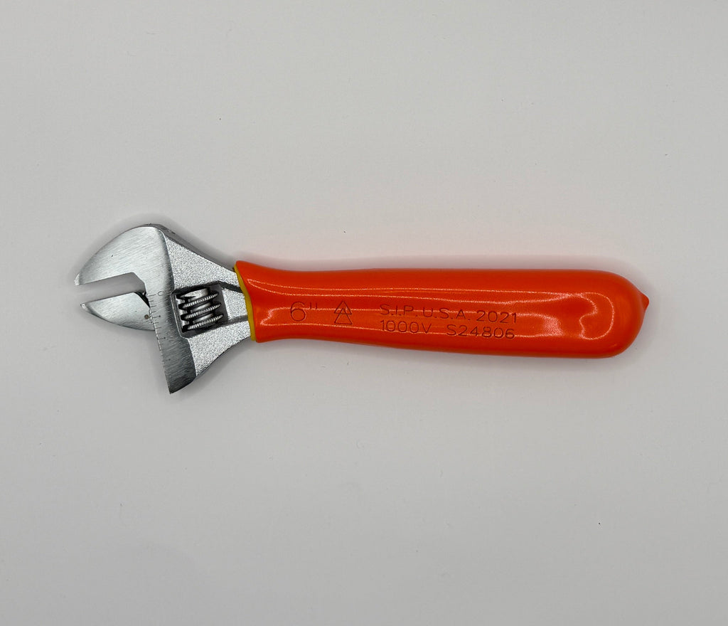 A small adjustable wrench with a bright orange handle and silver metal head, photographed inside a white box corner.
