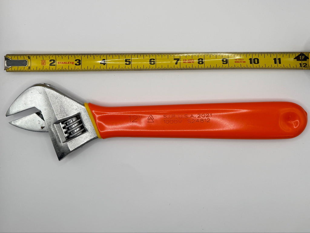 A yellow tape measure standing upright next to an adjustable wrench with a bright orange handle, photographed against a plain white wall.