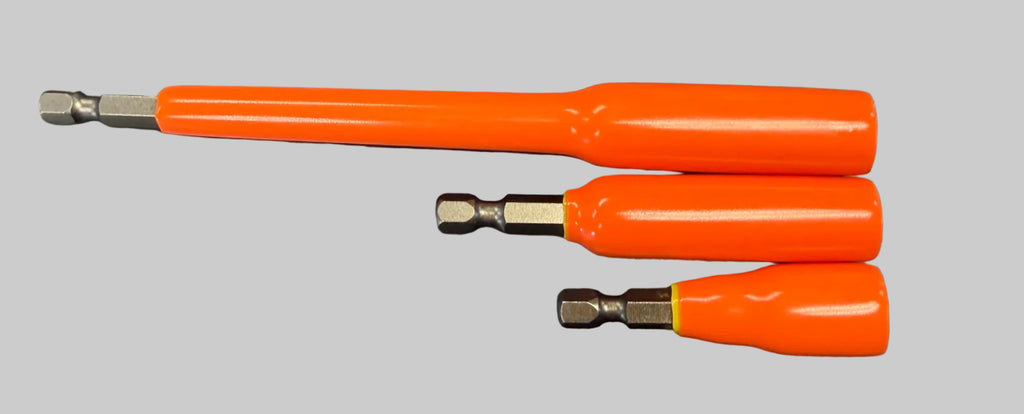 Three orange-handled screwdriver bits with silver metal shafts laid out on a dark gray desk surface.